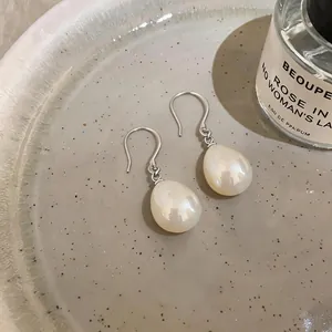 Close-up of elegant waterdrop pearl earrings presented on a decorative ceramic tray.