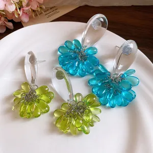 Close-up detail of blue and lime green resin teardrop pendant earrings on white plate