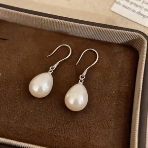 Close-up of elegant teardrop pearl earrings with silver hooks in a jewelry box