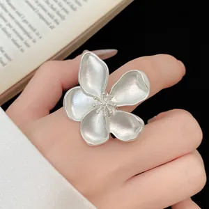 Detailed macro view of a silver-toned vintage flower ring with matte texture on a hand