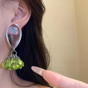 Macro detail view of elegant green resin bead tassel earrings worn on a model's ear