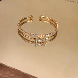 Primo piano di un bracciale a doppio strato con fiocco dorato e pavé di zirconi cubici.
