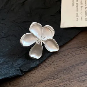 Macro view of a matte silver retro flower-shaped jewelry piece with fine petal details.