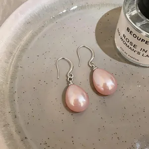 Elegant detail of French style waterdrop pink pearl earrings with silver hooks on a plate