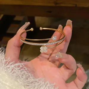 Vista dettagliata di un elegante bracciale rigido dorato a doppio strato con ciondoli CZ