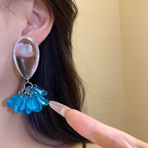 Detailed view of fashionable blue resin water drop tassel drop earrings on a model's ear