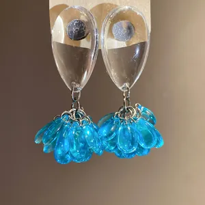 Close-up of translucent blue resin teardrop tassel earrings with silver needle posts