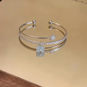 Dettaglio bracciale rigido a doppio strato in argento con zirconi e ciondolo a quadrifoglio