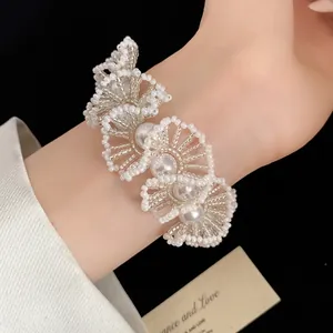 Nahaufnahme eines handgefertigten floralen Accessoires aus weißen Perlen am Handgelenk