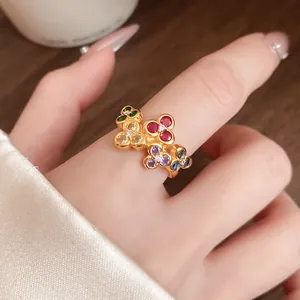 Macro view of vintage gold-toned open ring with five colorful zircon flower motifs.