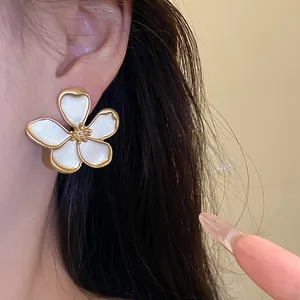 Macro shot of an elegant gold-rimmed white petal flower earring worn on a model's ear