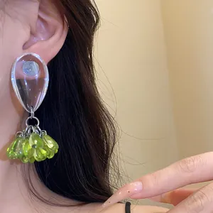 Close-up detail of a minimalist resin teardrop earring with green bead tassels on ear