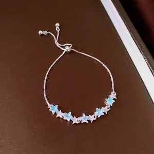 Bracelet étoile en argent élégant avec breloques en zircon bleu sur fond brun luxueux