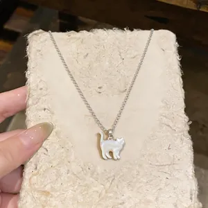 Detail macro of a delicate cat pendant necklace with shell inlay on textured paper.