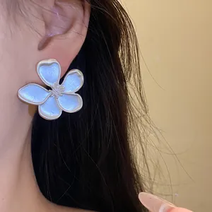 Detailed macro view of a large light blue vintage flower stud earring worn on the ear