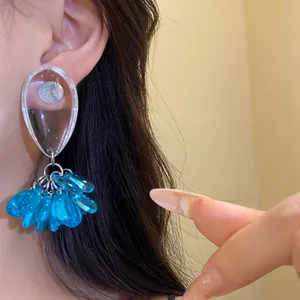 Detail shot of the stylish blue resin teardrop tassel earrings worn on the ear.