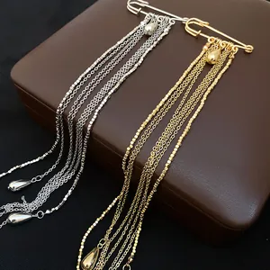 Detail of gold and silver metal tassel brooches with water drop charms on a jewelry box