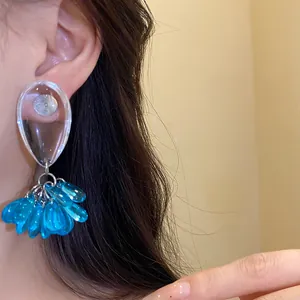 Detail view of stylish resin teardrop earrings with blue translucent bead tassels.