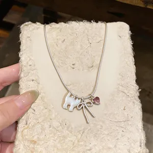 Detail view of dainty shell cat and bow pendant necklace with a pink heart charm