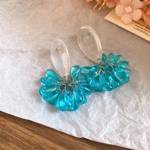 Close-up of blue resin water-drop tassel earrings with silver needles on textured paper