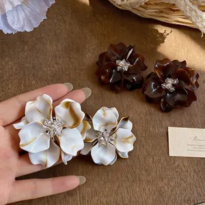 Elegant marbled floral stud earrings with beaded centers shown on a wooden background
