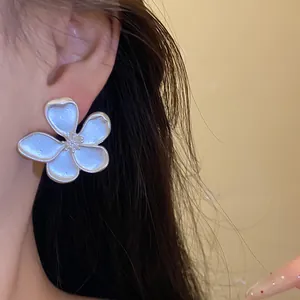 Close-up of a vintage matte silver flower earring worn on ear, showing delicate petals.