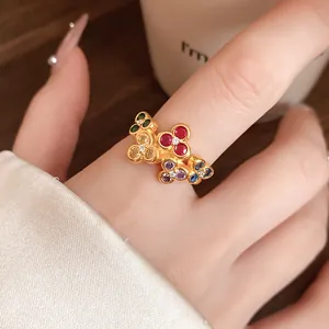 Close-up of a vintage gold flower open ring featuring vibrant multi-colored zircons on a finger.