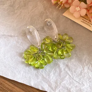 Macro detail view of elegant green resin teardrop cluster earrings on textured paper.
