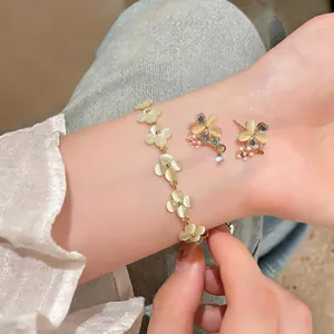 Vue macro détaillée des boucles d'oreilles fleurs en œil de chat et du bracelet doré assorti