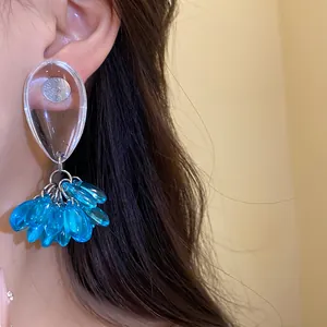 Close-up view of elegant blue resin teardrop tassel earrings worn on a model's ear