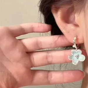 Close-up view of minimalist mint green flower pendant earring with silver hoop on ear
