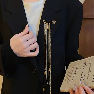 Detail of vintage gold safety pin brooch with long chain tassels on a black blazer.