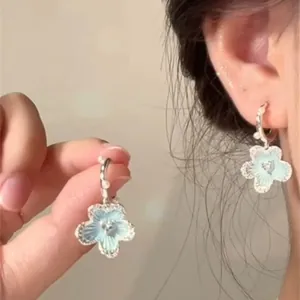 Detailed view of light blue flower earrings with pearls on a silver-colored hoop