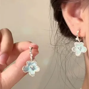 Detailed view of light blue flower earrings with pearl accents and silver studs.