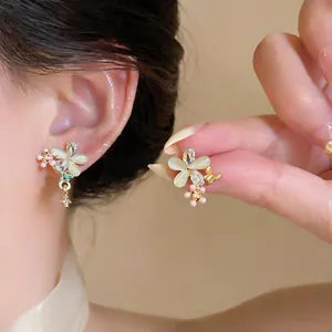 Détail exquis de boucles d'oreilles fleuries en pierre œil-de-chat et papillon