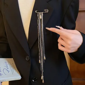Detailed view of a silver tassel brooch with water-drop pendants styled on a blazer