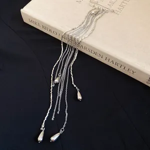 Macro detail of elegant silver metal brooch featuring long multi-chain waterdrop tassels