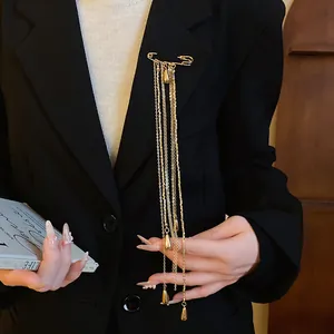 Detailed view of vintage gold safety pin brooch with long water drop tassels on a black blazer