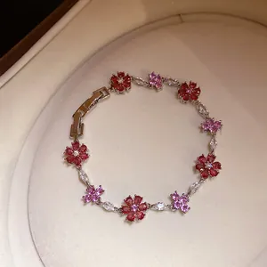 Gedetailleerde weergave van een bloemenarmband met roze en rode zirkoniasteentjes