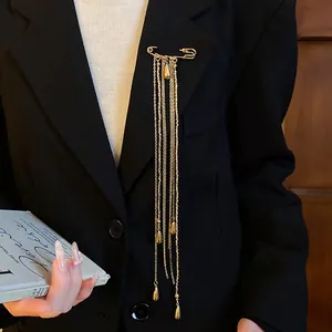 Close-up detail of a vintage gold-tone safety pin brooch with teardrop tassel chains