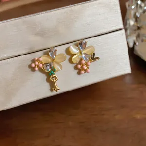 Détail rapproché de boucles d'oreilles fleurs asymétriques avec pierres œil-de-chat