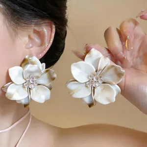 Detailed macro view of large white floral earrings with beaded centers on model