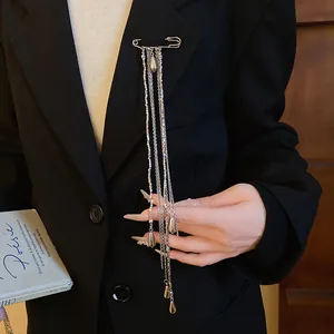 Close-up detail of a vintage silver metal waterdrop tassel brooch on a black blazer.
