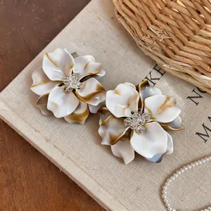Detailed macro view of marbled ivory flower earrings with crystal beaded centers
