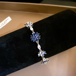 Detailweergave van een elegante zilveren armband met blauwe zirkonia-bloemen