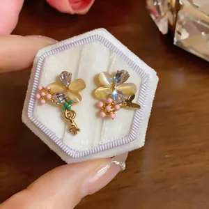 Détail rapproché des boucles d'oreilles élégantes en pierre d'œil de chat et papillon