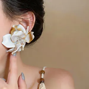 Macro detail of a large elegant white marbled flower earring worn by a female model