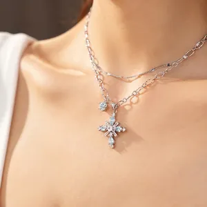 Double-layered silver chain necklace with sparkling zircon cross pendant on a model