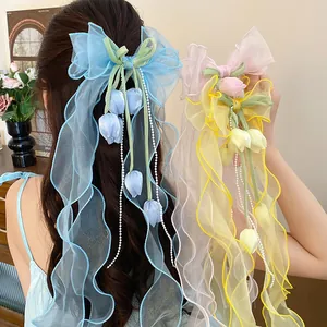 Dettaglio di eleganti fermagli per capelli in organza con ciondoli a tulipano e lunghi nastri