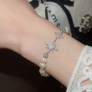 Detailed view of elegant pearl bracelet with sparkling zircon star charms on female wrist